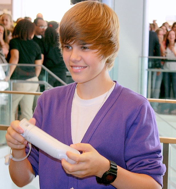 Justin Bieber, NYC September 2009 — the iconic swoop era, in a purple cardigan, smiling. Photo by Kerosene Photography (CC BY 2.0).